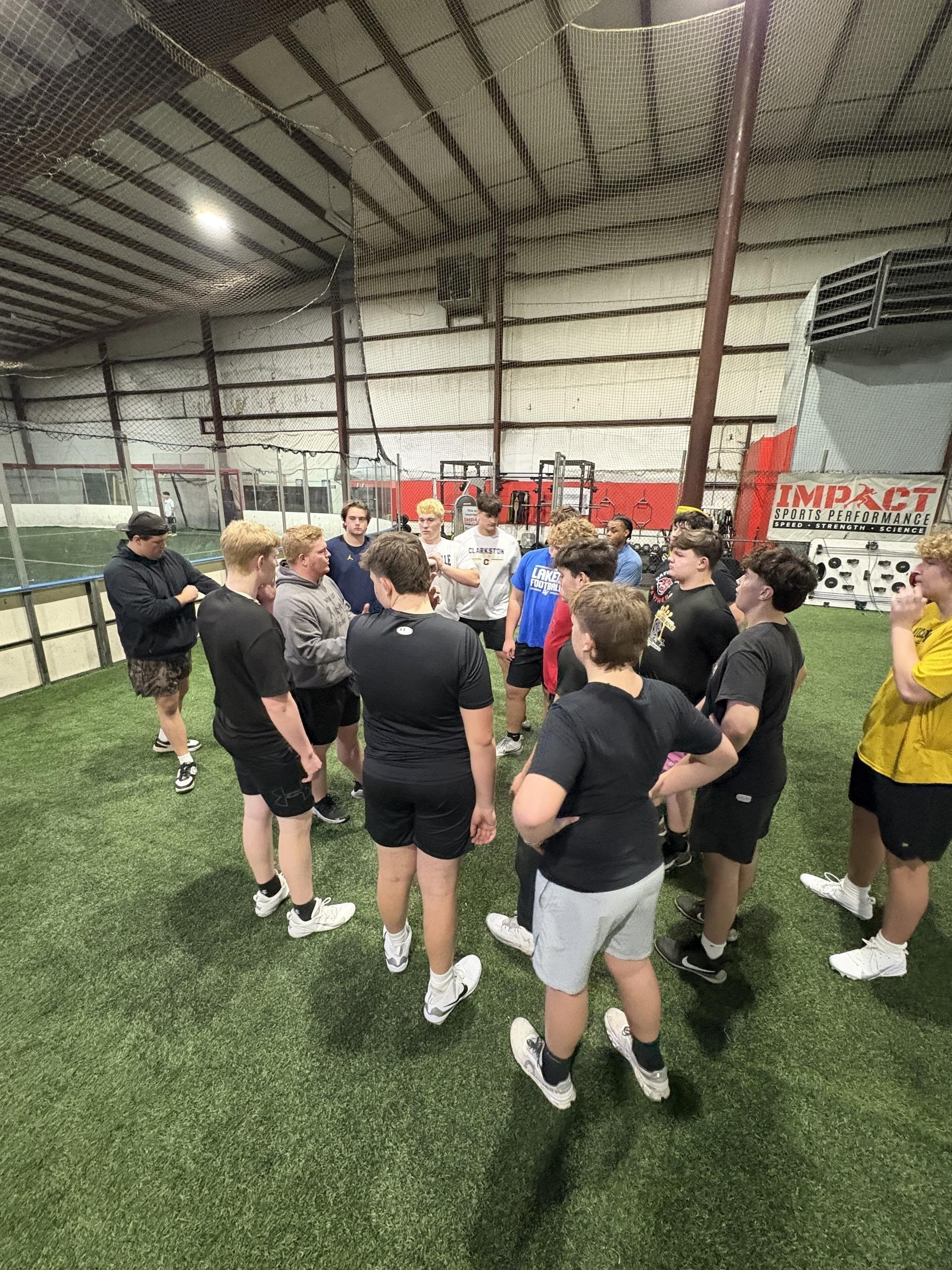 Win Up Front athletes in training huddle on indoor turf
